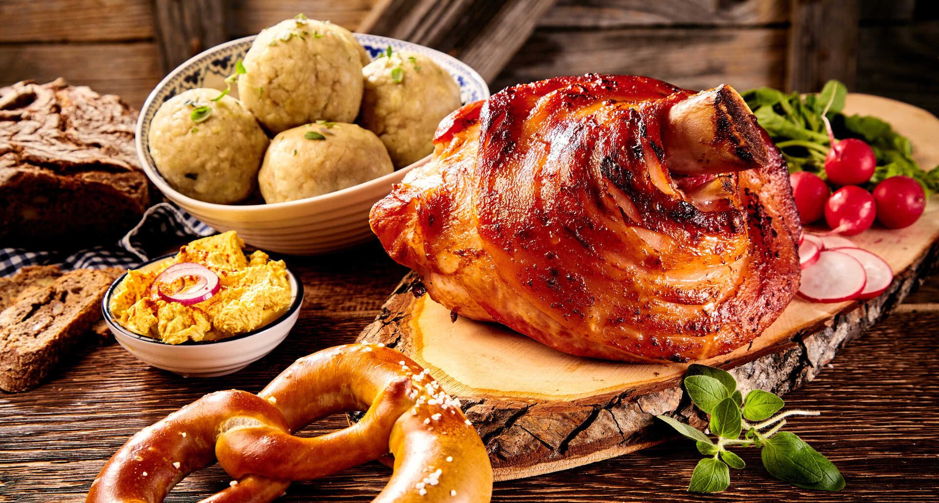 Ein Tisch mit einer Vielzahl von Speisen, darunter Brezeln, Fleisch und Brot