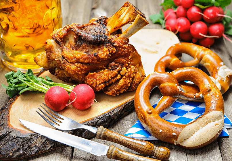 Ein rustikaler Holztisch, dekoriert mit frischen Brezeln und einem Glas Bier