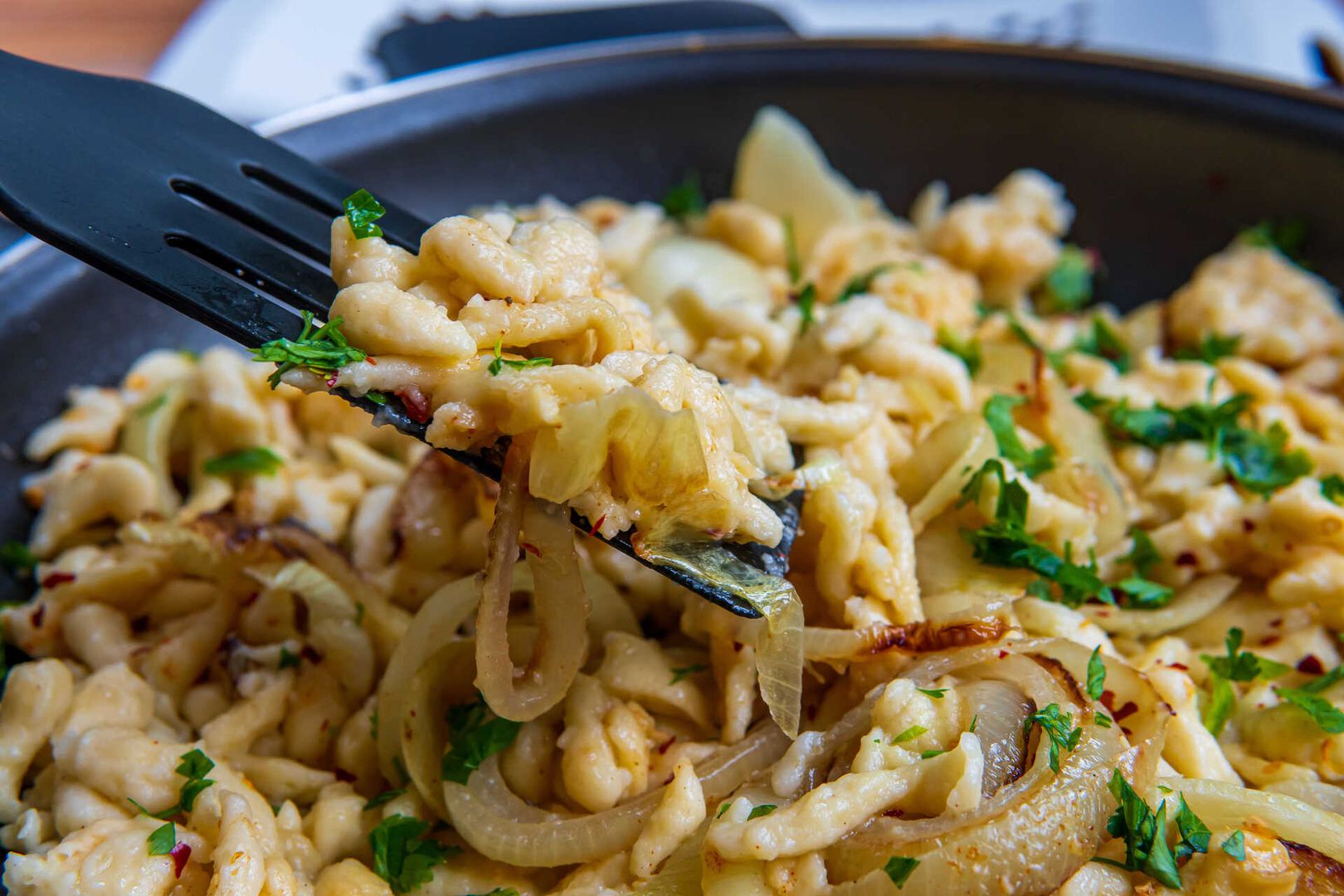 Eine Gabel liegt in einer Pfanne mit zubereitetem Essen